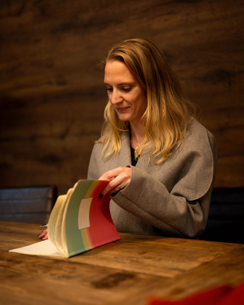 Elisabeth Wadin bläddrar i en bok vid ett träbord.