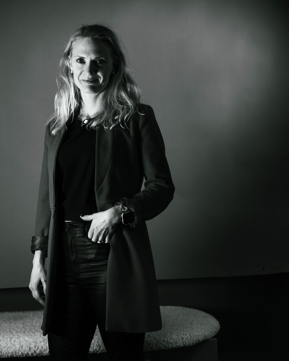 Svartvitt porträtt av Elisabeth Wadin, stående med handen i sidan mot en mörk bakgrund.